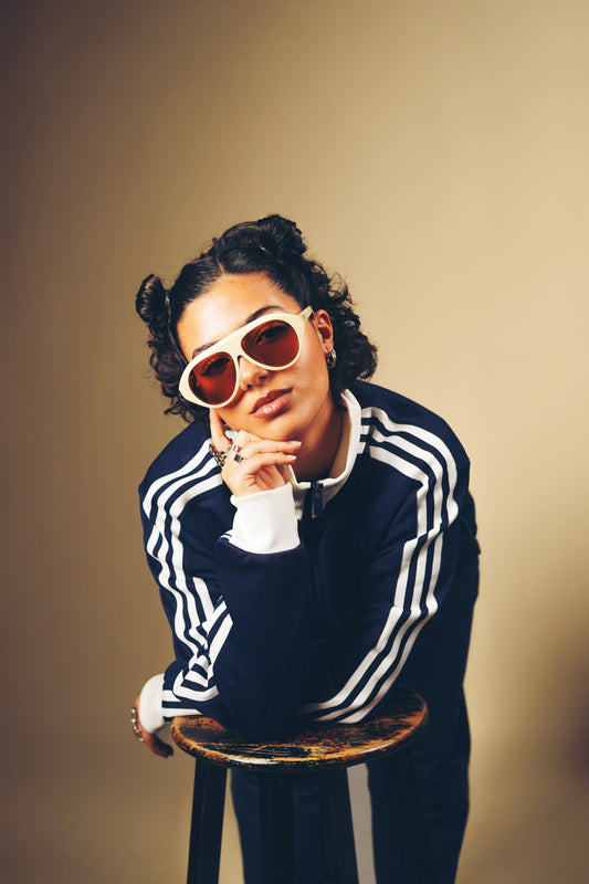Femme qui pose avec des Lunettes de soleil beige aux nuances douces et naturelles de la marque VROC. 