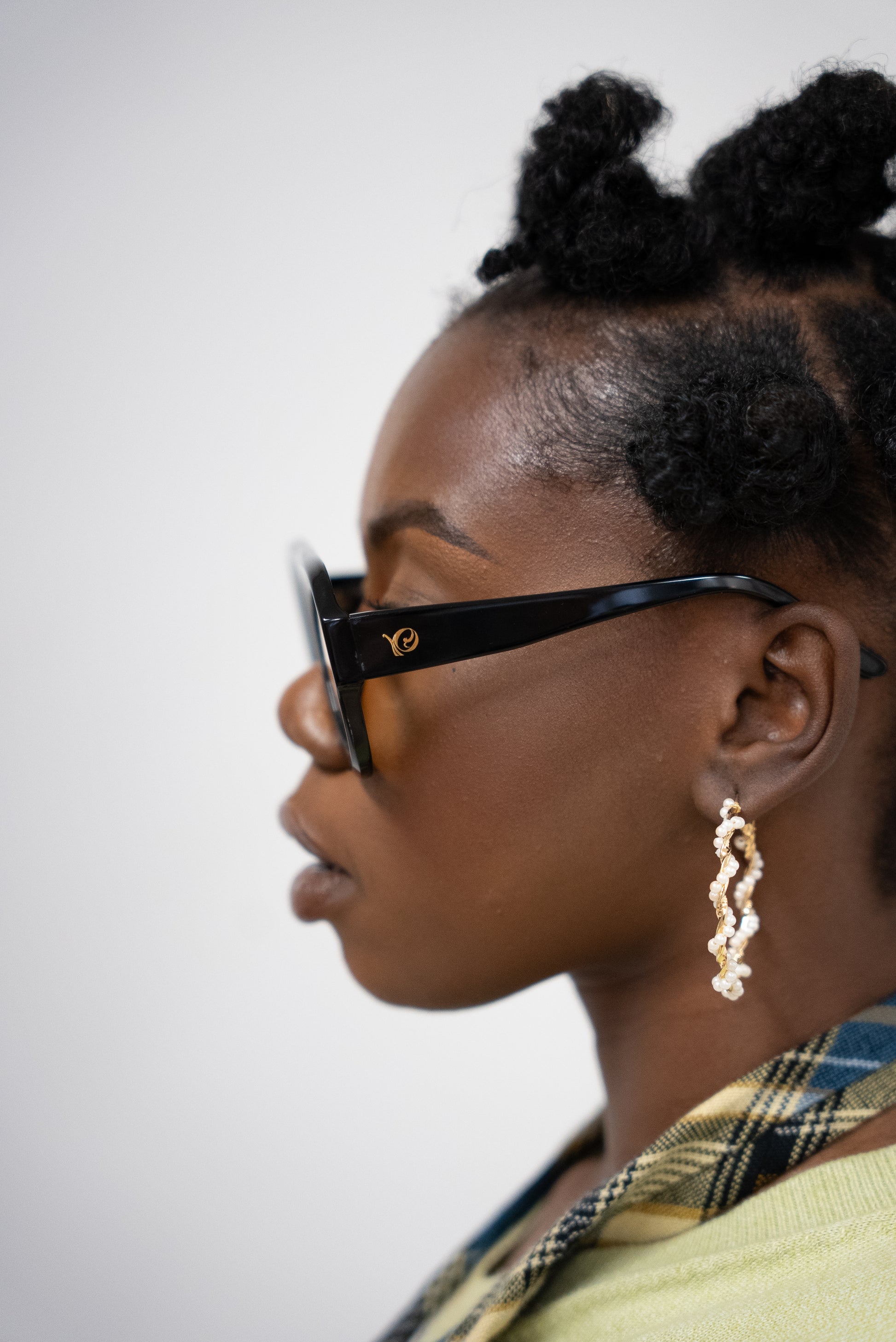 Photo d'une femme de profile qui porte  Lunettes de soleil noires aux verres teintés jaune doré de la marque VROC. 