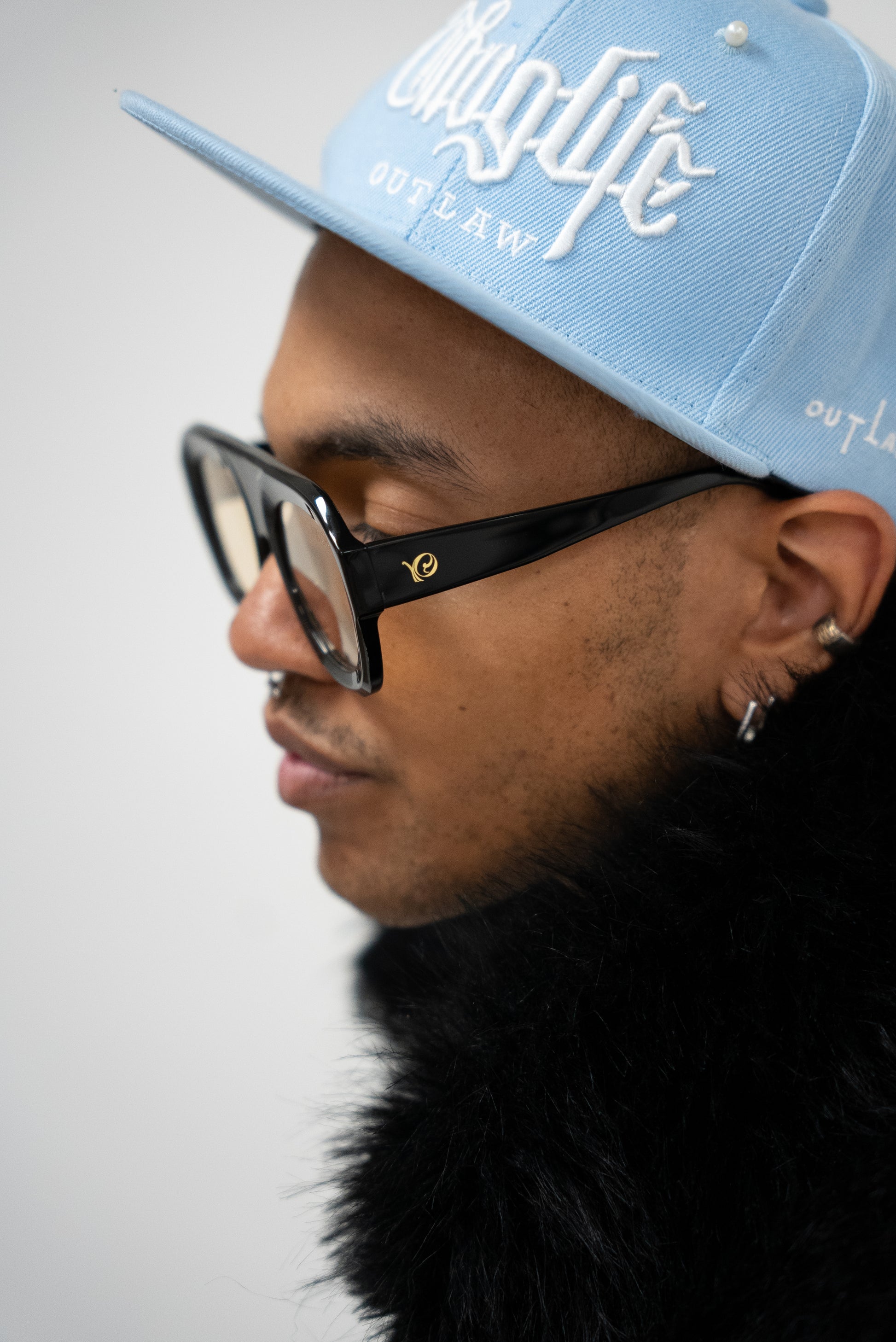 Photo d'un homme de profile qui porte des Lunettes de soleil noires aux verres teintés jaune doré de la marque VROC. 