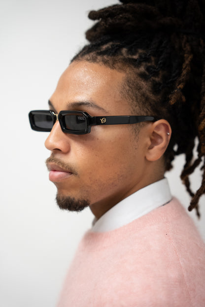 phto d'un homme de profile avec des Lunettes de soleil noires à la monture fine et aux lignes structurées de la marque VROC.