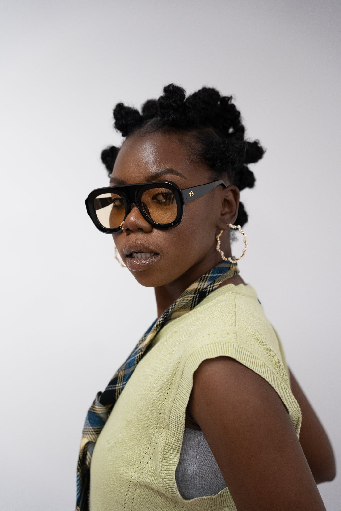 Photo d'une femme qui porte des Lunettes de soleil noires aux verres teintés jaune doré de la marque VROC. 
