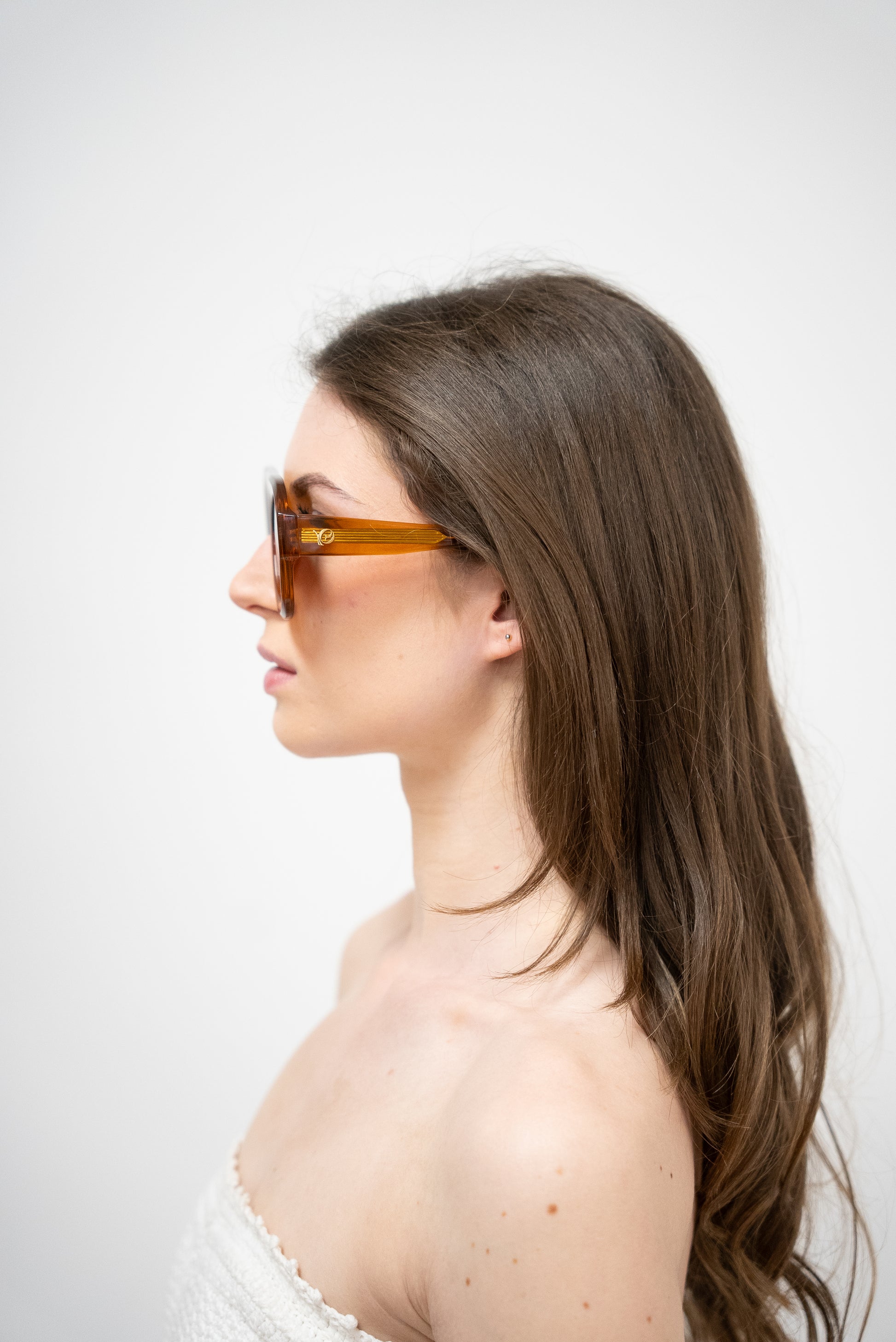 Photo d'une femme de profile qui porte des Lunettes de soleil orange translucide aux teintes ambrées profondes de la marque VROC. 